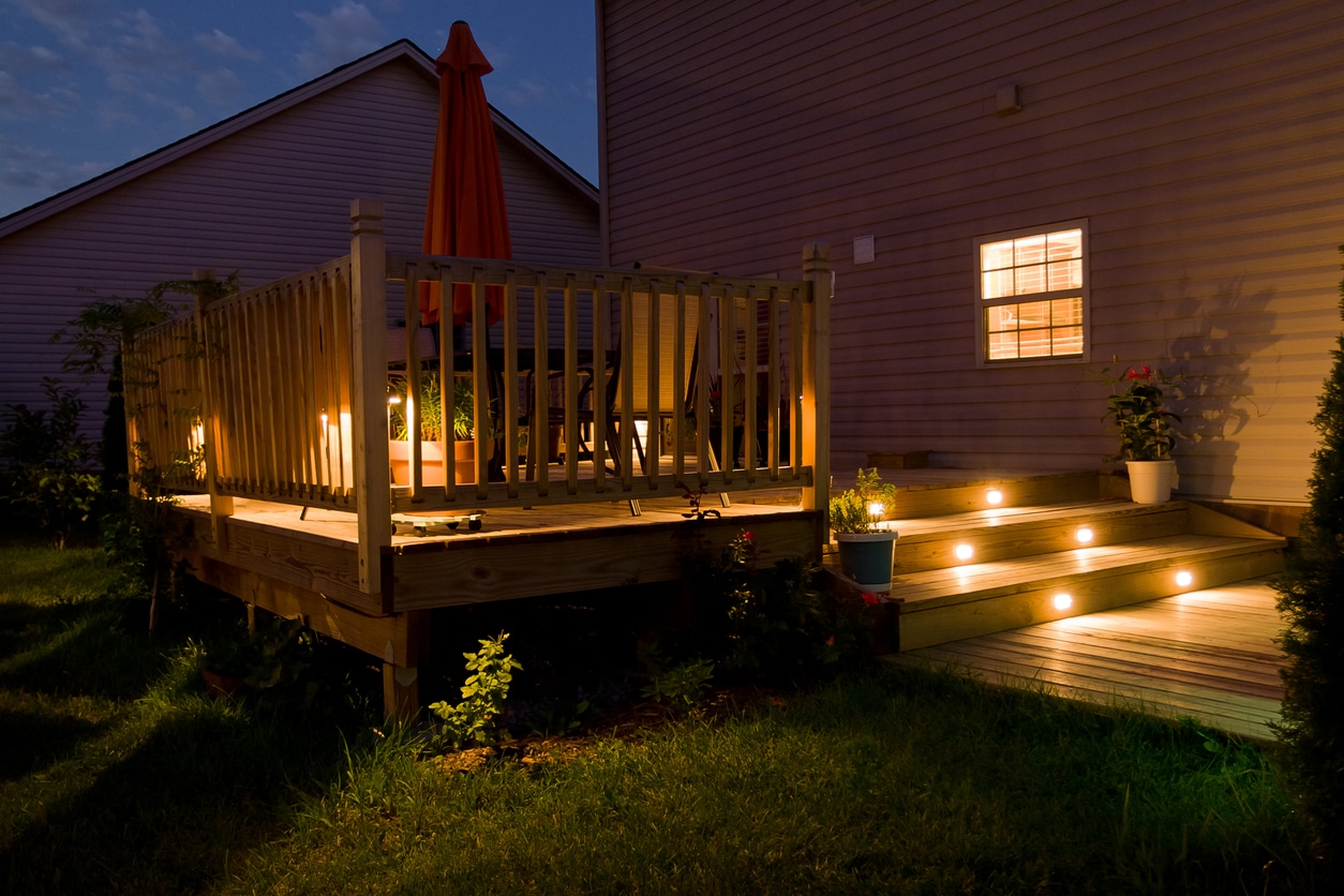 Deck lit at night with low-voltage stair riser and perimeter lighting
