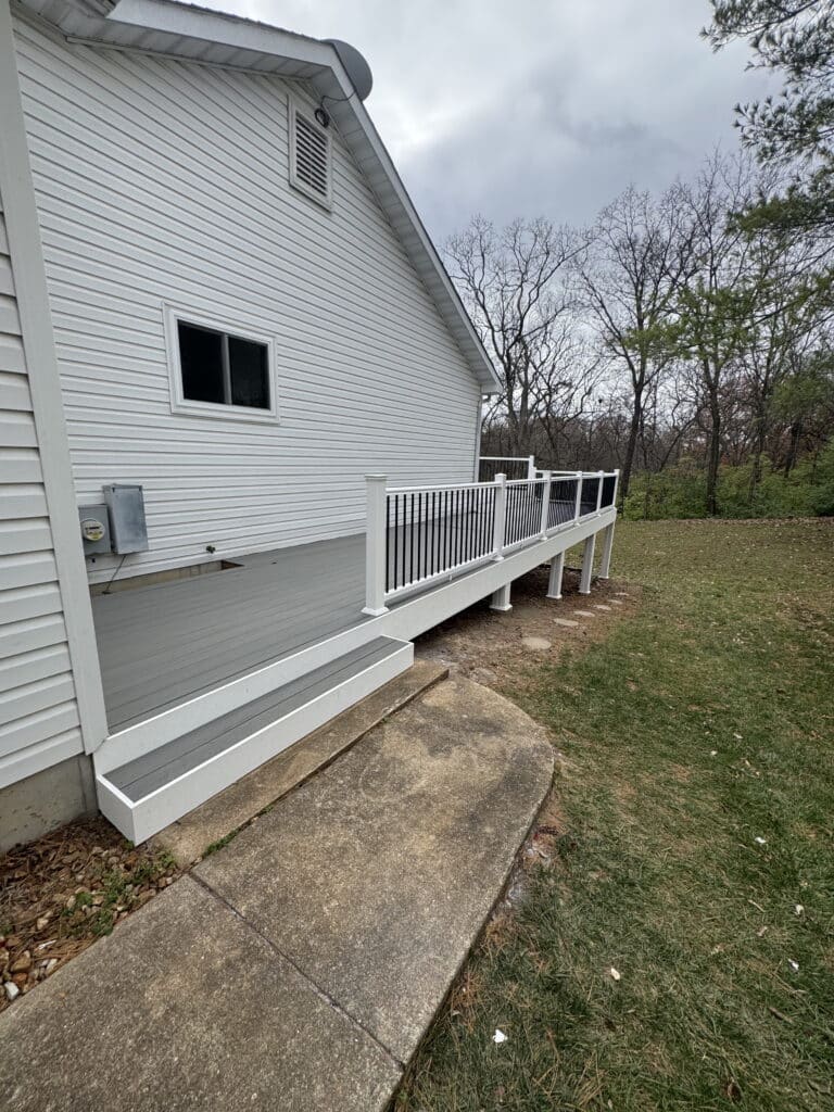 Exterior view of a gray composite deck with white vinyl railing