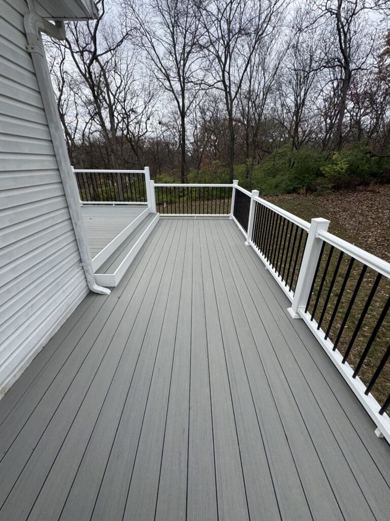 White vinyl deck railing with black balusters along a gray composite deck