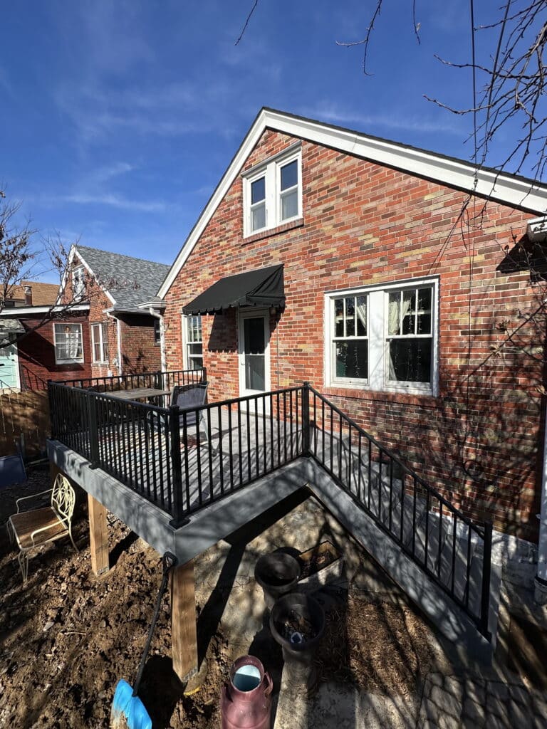 Black aluminum deck railing wrapping a raised deck on a brick home