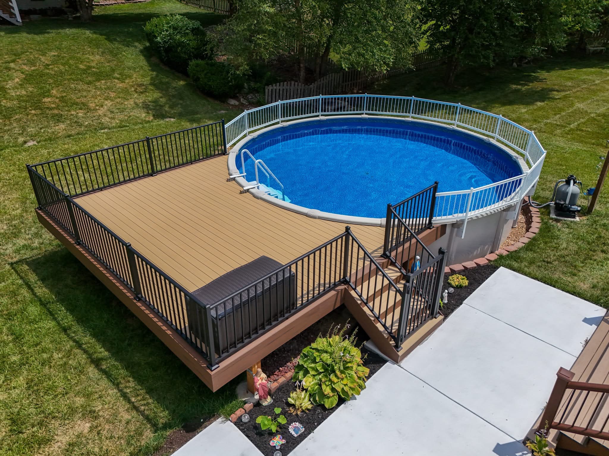 Above-ground pool with a composite pool deck, black aluminum railing, and white pool-code fence