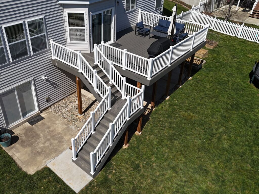 Aerial view of a TimberTech Silver Maple composite deck with white Veranda vinyl railing and switchback stairs, O'Fallon MO