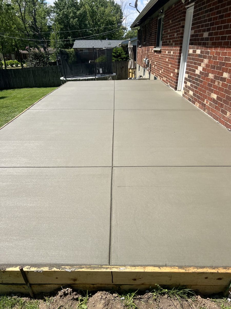 Freshly poured broom finish backyard patio along a brick house in St. Louis