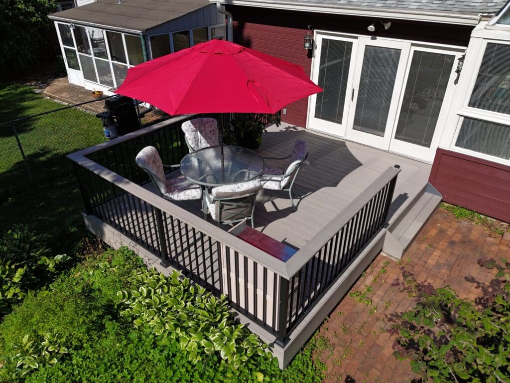 Gray composite deck with black aluminum railing and steps to a brick patio, St. Louis